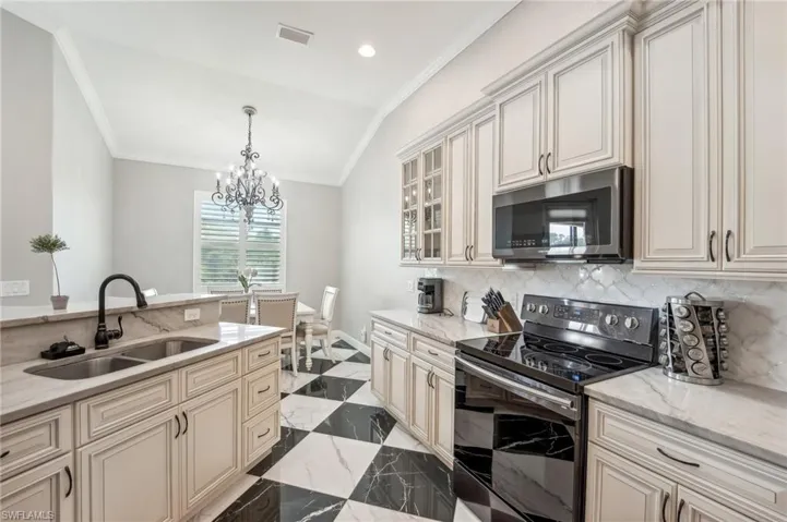 Kitchen featuring custom cabinetry with dark hardware, stone countertops and backsplash, stainless steel double basin sink with matte black faucet, and a black and white checkered tile floor