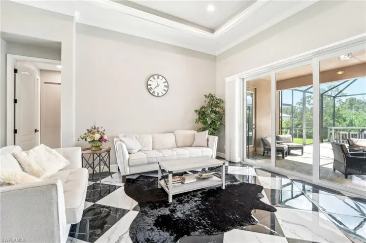 Spacious living area featuring large format black and white checkered tile flooring, a tray ceiling, and crown molding