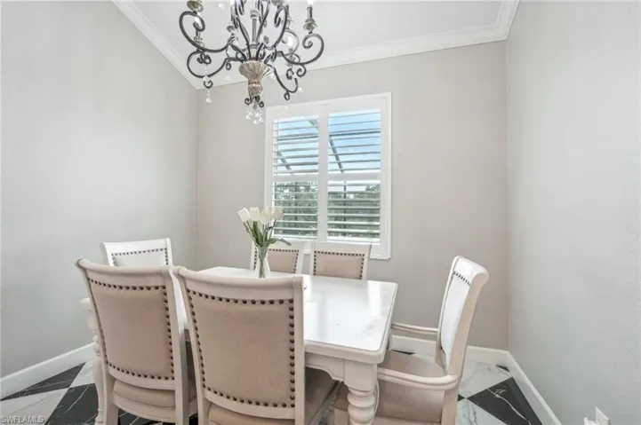 Dining area featuring a decorative chandelier, crown molding, and a window with plantation shutters