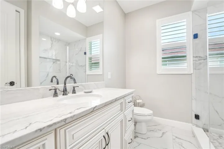 Bathroom featuring a vanity with a white stone countertop, undermount sink, and dark bronze-finish fixtures