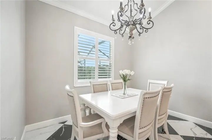 Formal dining space featuring a decorative chandelier, crown molding, and plantation shutters