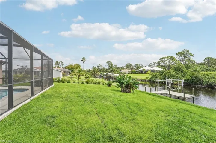 Expansive green lawn sloping towards a waterfront with a private dock and boat lift