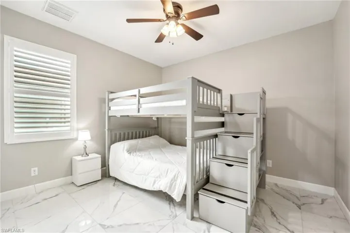 Room with large format tile flooring, a window with louvered shutters, and a ceiling fan with integrated lighting