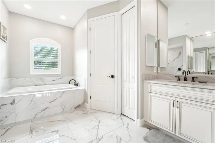 Bathroom featuring large-format tile flooring and a built-in soaking tub with coordinating tile surround
