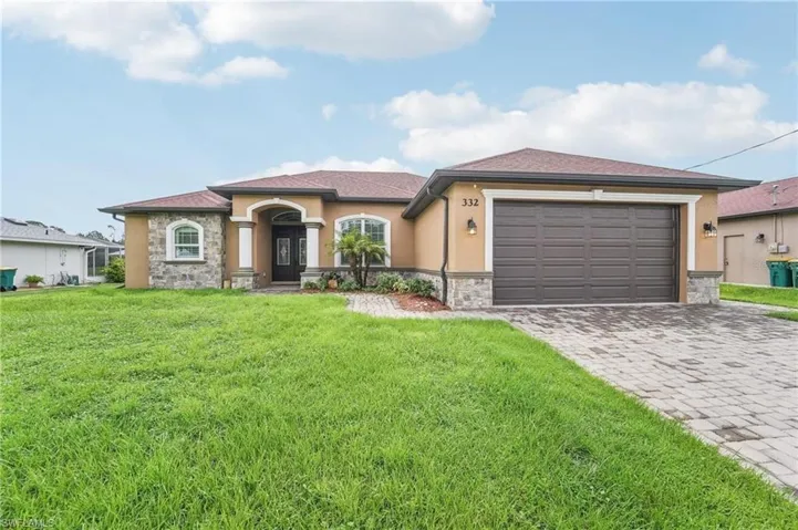 Stucco exterior with stone veneer accents, an arched entry, a two-car garage, an arched window, and a paver driveway