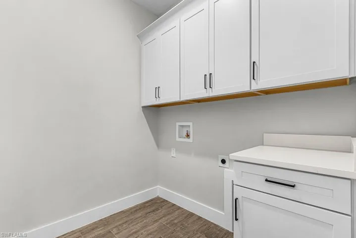 Laundry area with dark wood-type flooring, cabinet space, hookup for a washing machine, and electric dryer hookup