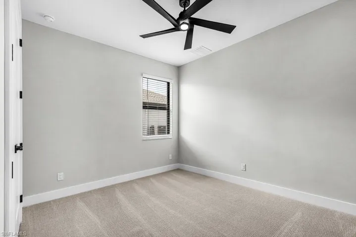 Carpeted empty room featuring baseboards and ceiling fan