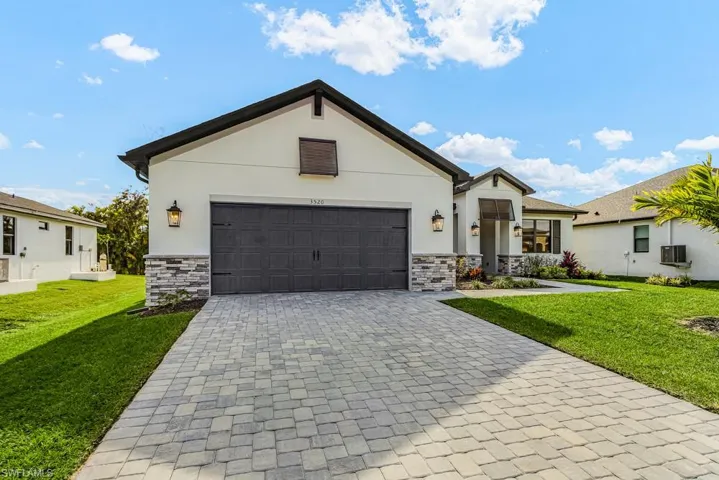 View of front of property with a front yard, decorative driveway, and stucco siding