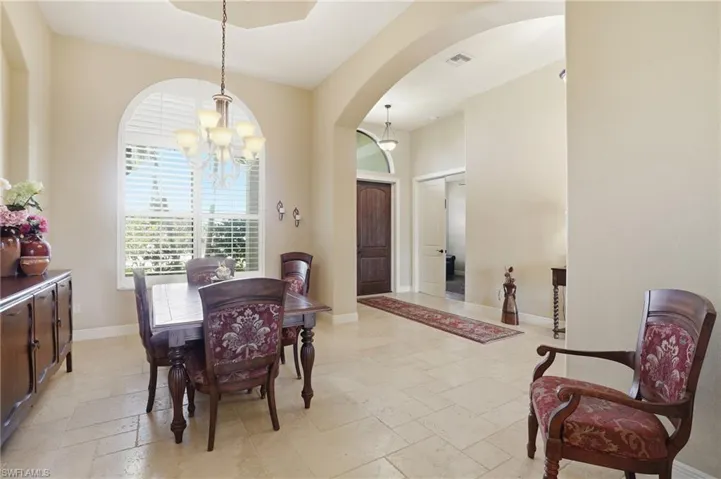 Dining area with arched walkways, stone tile floors, and suspended lighting