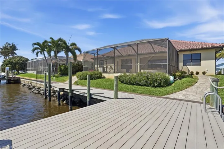 Dock with a sunroom, glass enclosure, a water view, and a lawn