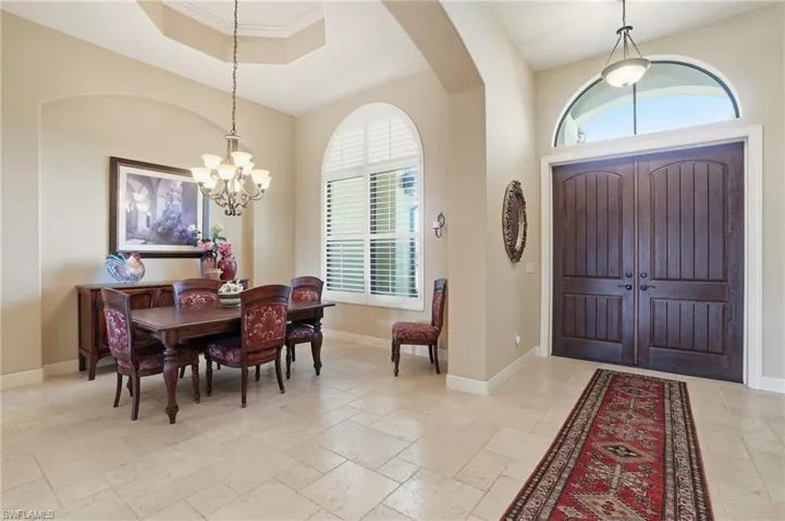 Foyer featuring stone tile flooring, hanging lights, a tray ceiling, and arched walkways