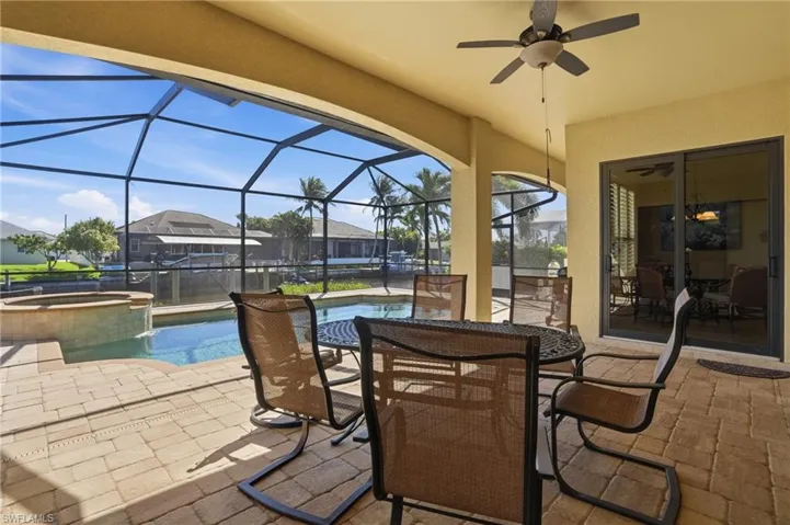 View of patio / terrace with a sunroom, ceiling fan, a pool with connected hot tub, glass enclosure, and outdoor dining space