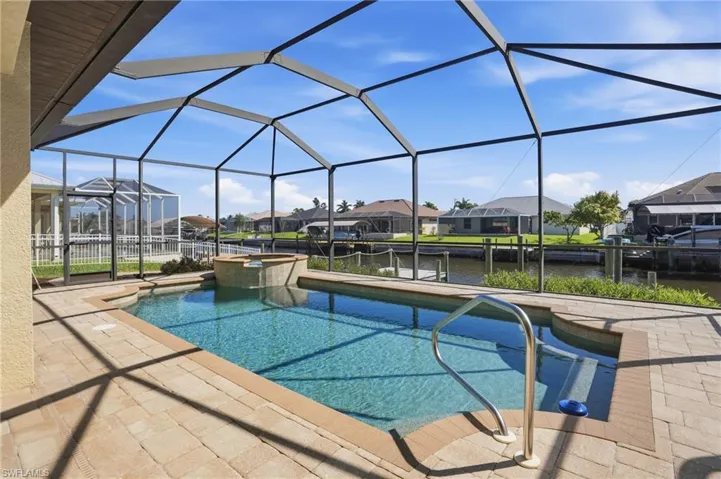 Integrated pool / spa featuring a residential view, a sunroom, a patio, a water view, and glass enclosure
