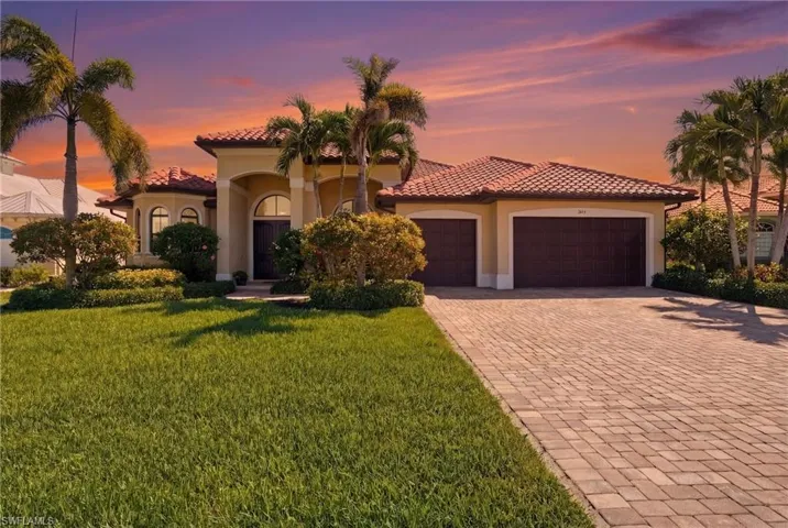 Mediterranean / spanish home featuring decorative driveway, stucco siding, a garage, a front yard, and a tiled roof