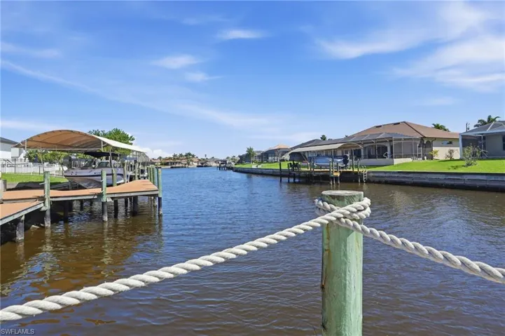 Dock area with a water view, boat lift, and a residential view
