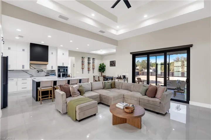 Living area with ceiling fan, a high tray ceiling, and recessed lighting