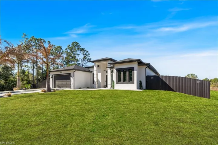 View of front of home featuring stucco siding, an attached garage, a gate, and concrete driveway