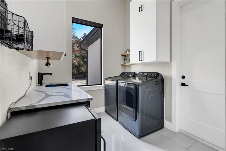 Laundry area with cabinet space, light tile patterned floors, and washing machine and dryer