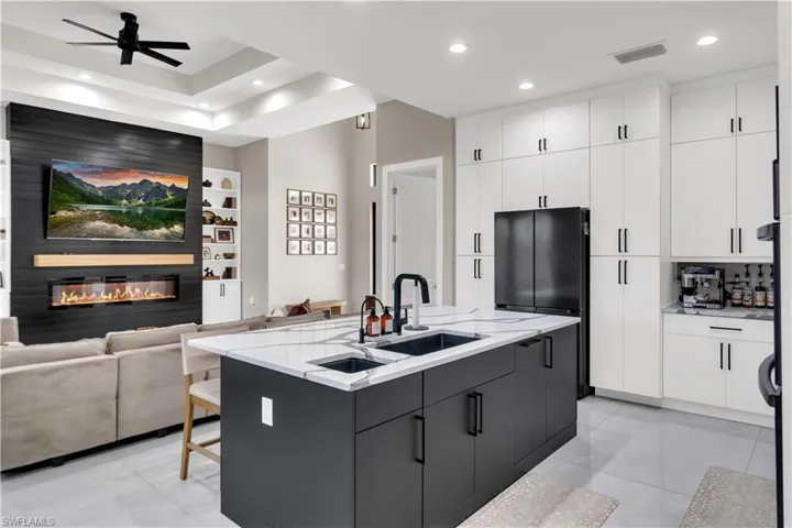 Kitchen featuring open floor plan, a center island with sink, modern cabinets, two tone cabinets, and a ceiling fan
