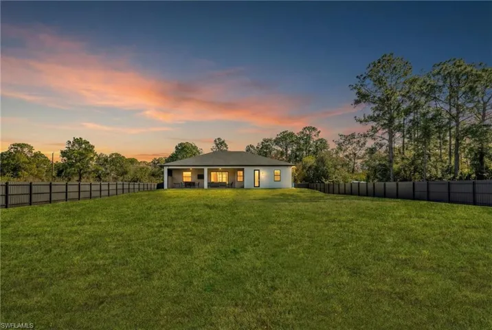 Back of house at dusk featuring a fenced backyard and a patio