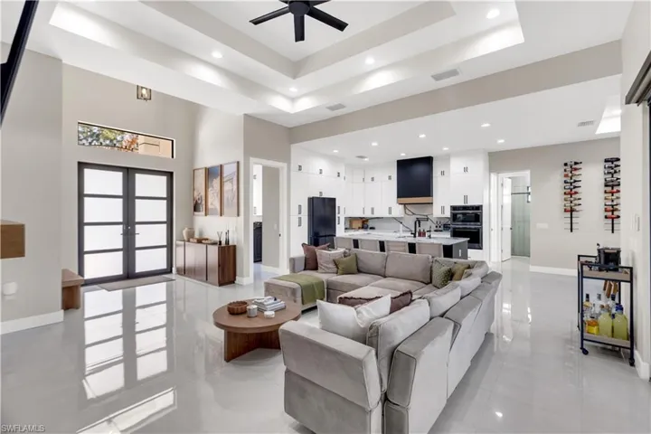 Living area with a tray ceiling, a ceiling fan, french doors, and recessed lighting