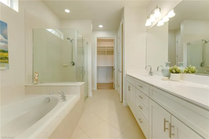 Bathroom featuring tile patterned flooring, shower with separate bathtub, and dual vanity