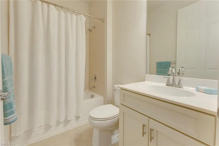 Full bathroom with shower / tub combo, tile patterned floors, toilet, and vanity