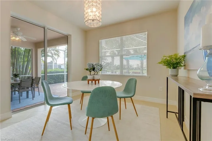 Dining space featuring light tile patterned floors, ceiling fan with notable chandelier, and plenty of natural light
