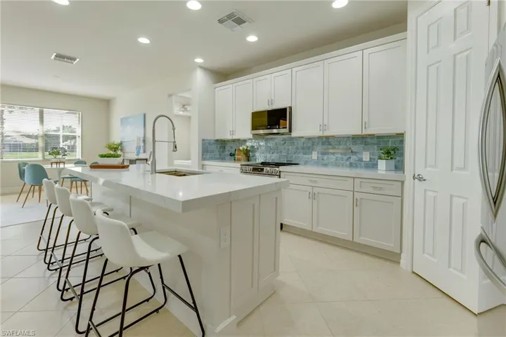 Kitchen featuring white cabinetry, sink, stainless steel appliances, and a kitchen island with sink