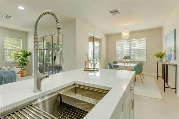 Kitchen with light tile patterned floors, pendant lighting, light stone countertops, and white cabinetry