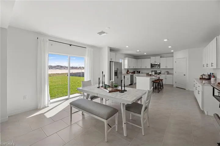 Open-concept layout featuring light-toned flooring, white cabinetry, and stainless steel appliances