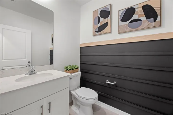 White vanity with a light-toned countertop, undermount sink, and chrome faucet