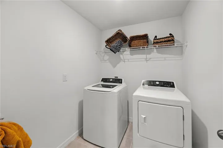Laundry area with tile flooring and a wire storage shelf