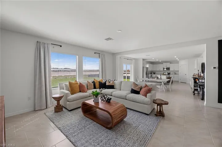 Expansive open-concept living area featuring light-toned tile flooring, large windows, and recessed lighting