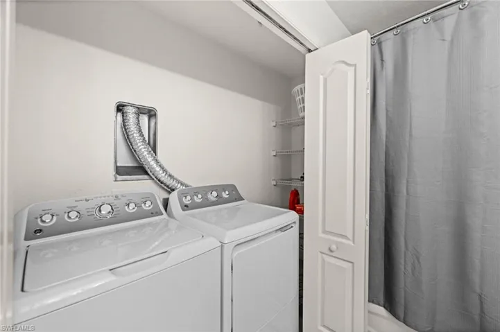 Dedicated laundry area featuring a white washing machine and dryer, a dryer vent, and a bi-fold door