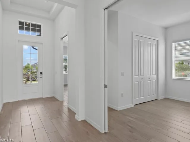 Entryway featuring a tray ceiling, baseboards, and wood finished floors