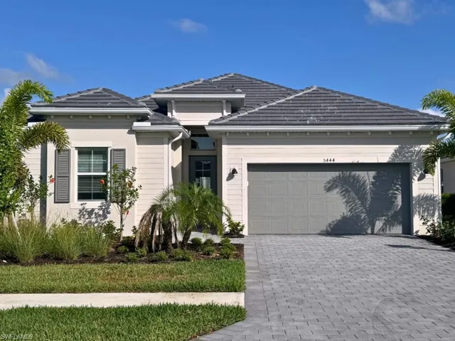 View of front facade featuring an attached garage, a tile roof, and decorative driveway