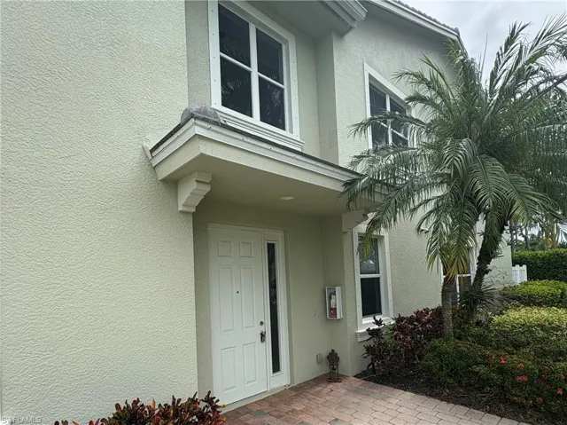 Stucco exterior with a covered entry featuring a white panel door and sidelight