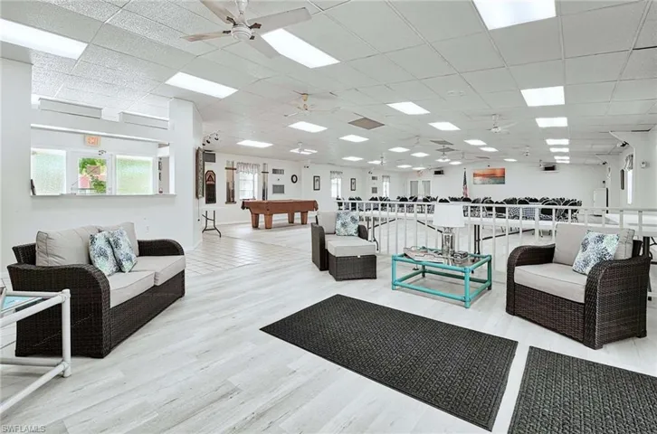 Living room with a paneled ceiling, pool table, ceiling fan, and light wood-type flooring