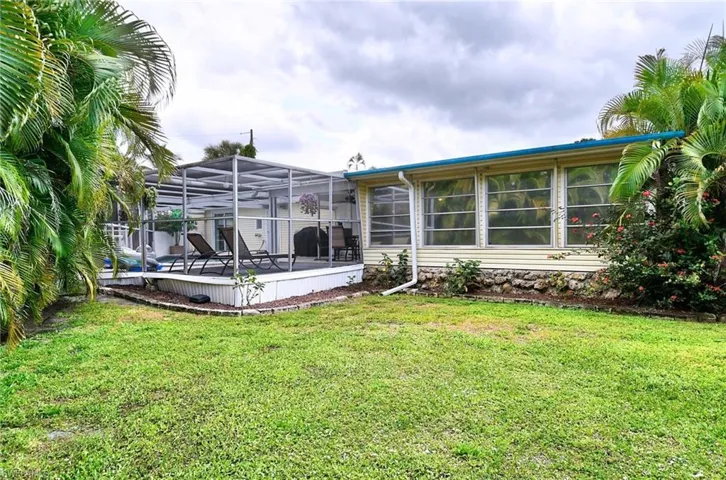 Back of property with a lawn and a lanai