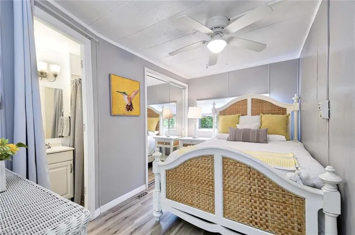 Bedroom featuring light hardwood / wood-style floors, connected bathroom, ornamental molding, and ceiling fan