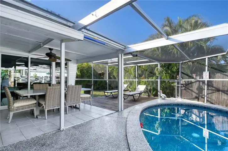 View of pool with ceiling fan, a patio, and glass enclosure