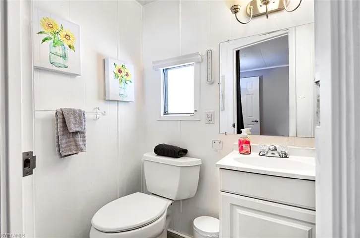 Bathroom with vanity with extensive cabinet space, crown molding, and toilet