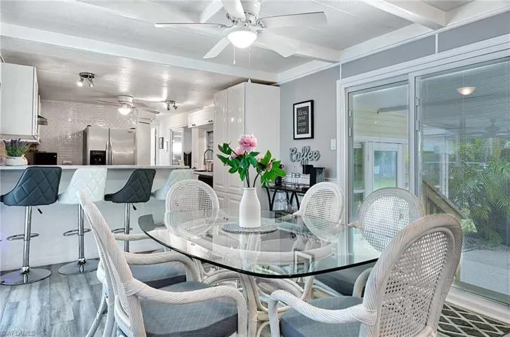 Dining room with ceiling fan, light wood-type flooring, and beam ceiling