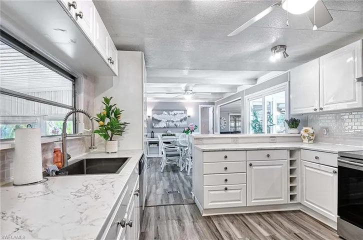 Kitchen featuring a wealth of natural light, white cabinets, and ceiling fan