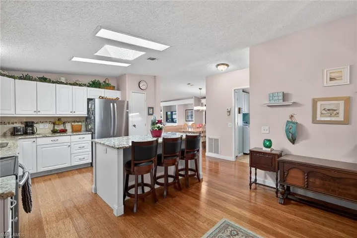 Kitchen featuring white cabinets, a skylight, appliances with stainless steel finishes, a center island, and a kitchen breakfast bar