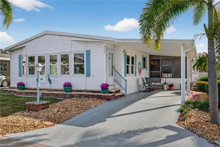 Manufactured / mobile home with a carport, a sunroom, entry steps, and concrete driveway