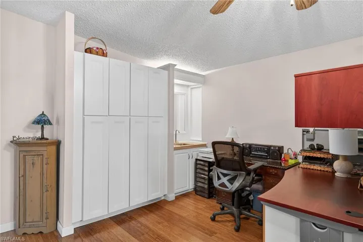 Office with a textured ceiling, light wood-style flooring, and ceiling fan