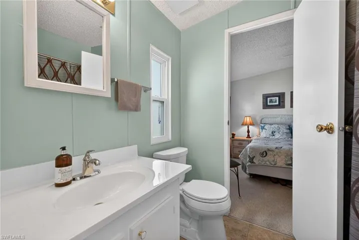 Bathroom featuring a textured ceiling, a shower with shower curtain, vanity, connected bathroom, and light carpet