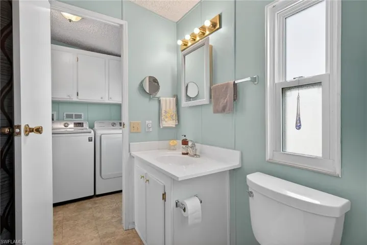 Bathroom with a textured ceiling, healthy amount of natural light, vanity, and washing machine and clothes dryer